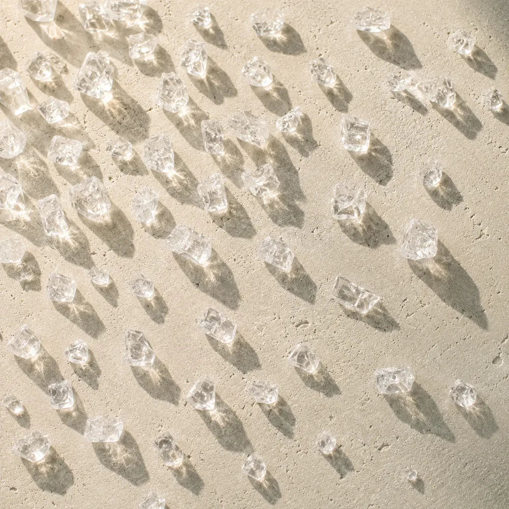 Clear mineral salt crystals scattered on pale limestone